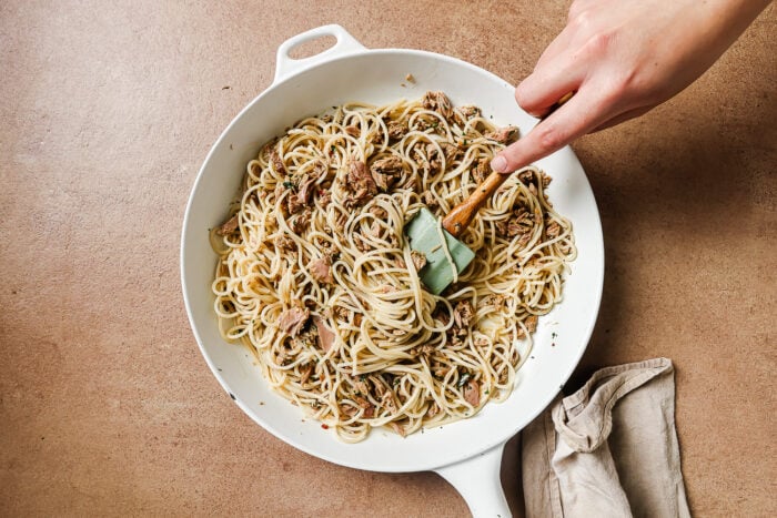 Cooked spaghetti added to the skillet with tuna and garlic sauce.