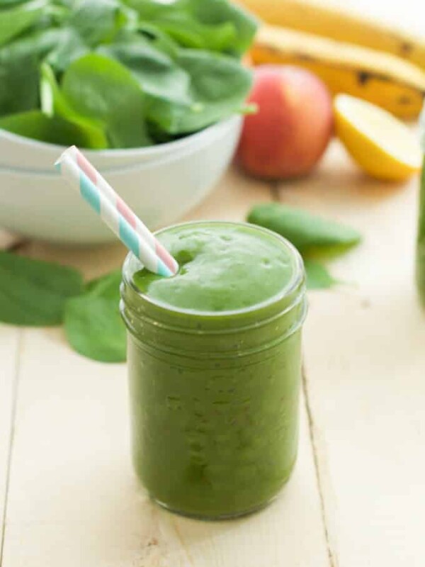 close up of a green smoothie in a mason jar with a straw