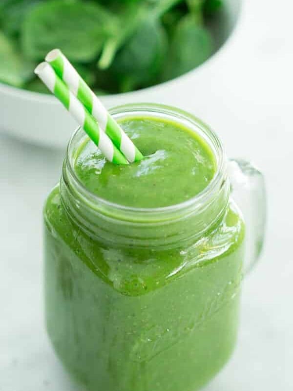 green smoothie in a mason jar with a straw