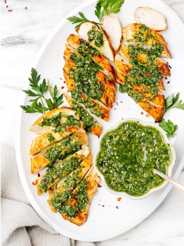 overhead chicken breast with chimichurri sauce on a white plate
