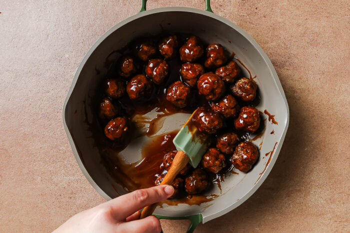 Cocktail meatballs simmering in sauce in a skillet.