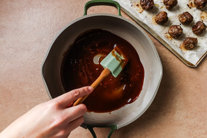 Cocktail meatballs simmering in sauce in a skillet.