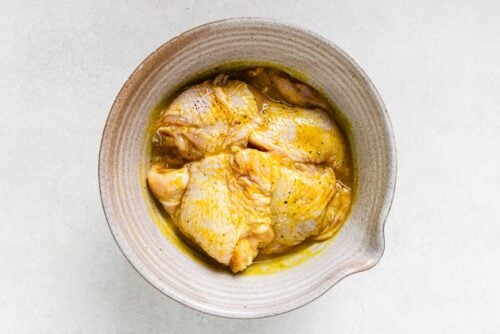 raw chicken thighs with Dijon dressing in a bowl