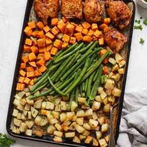 overhead view of a baking sheet containing chicken thighs and veggies