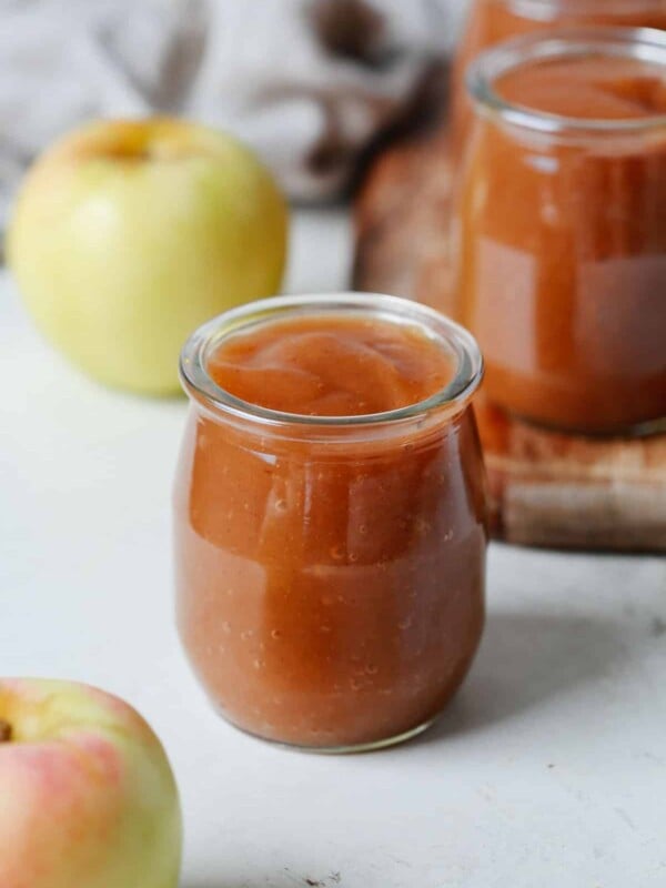 A close up of a small glass containing slow cooker apple sauce