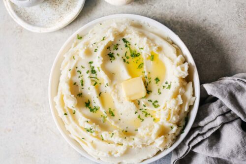 A large bowl of mashed potatoes with butter melted on top.