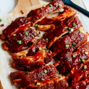 A close up of a baked ribs on a wooden cutting board