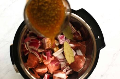 overhead view of beef broth being poured inside of an instant pot
