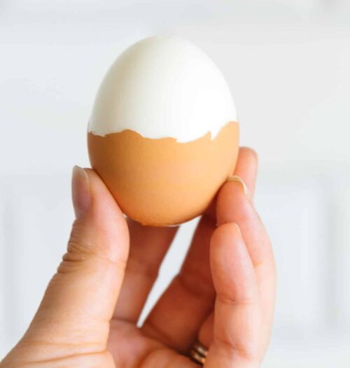 A hand holding a broiled egg