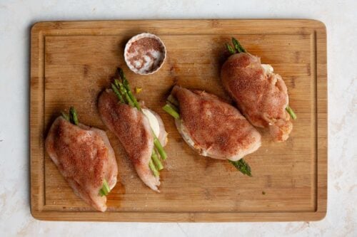 seasoned chicken breasts on a wooden board.