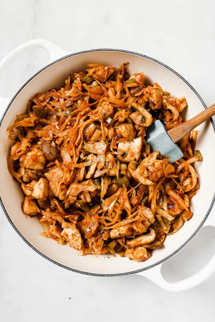 cooked chicken and cabbage in a white skillet
