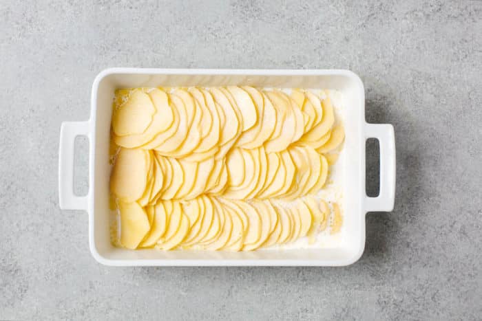 overhead view of white casserole containing sliced potato and heavy cream