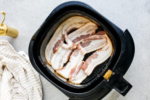 overhead view of raw bacon inside of a air fryer basket