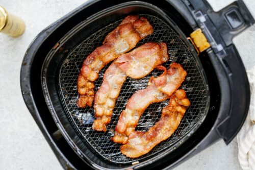 overhead view of cooked bacon inside of a air fryer basket