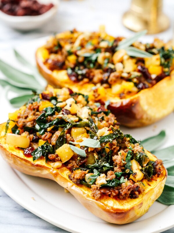 Stuffed butternut squash halves on a white serving plate.
