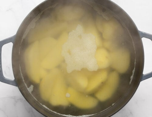Boiling peeled potatoes in a large pot of salted water for creamy mashed potatoes.