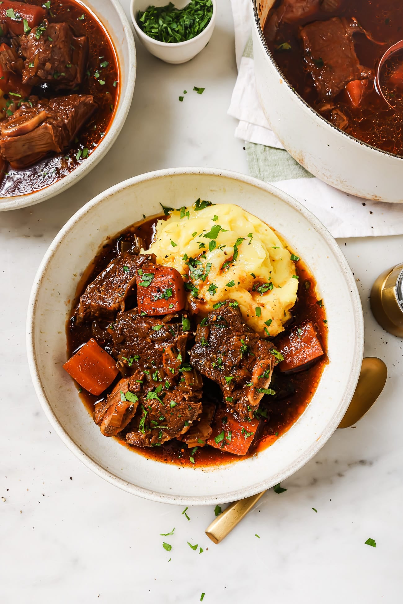 Guinness braised short ribs over mashed potatoes in a white bowl.