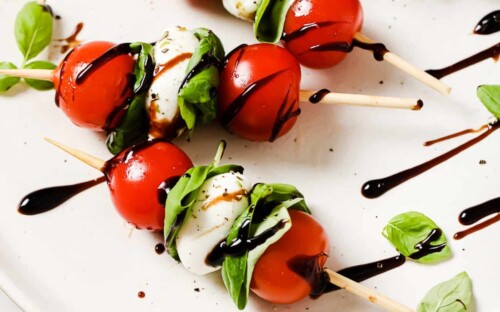 close up of caprese skewers on a white plate