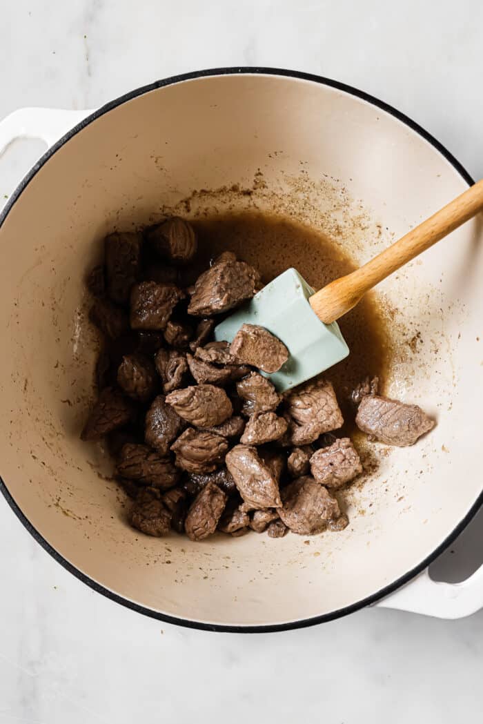 Seared pieces of beef in a large Dutch oven.