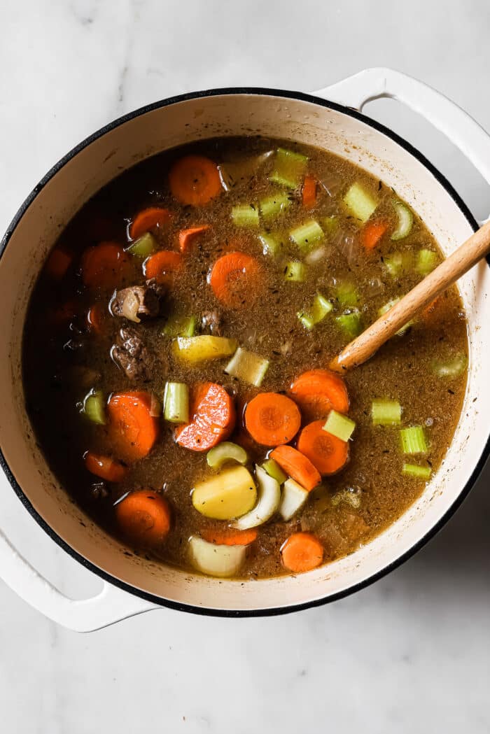 Carrots, celery, and onion are added to the Dutch oven.