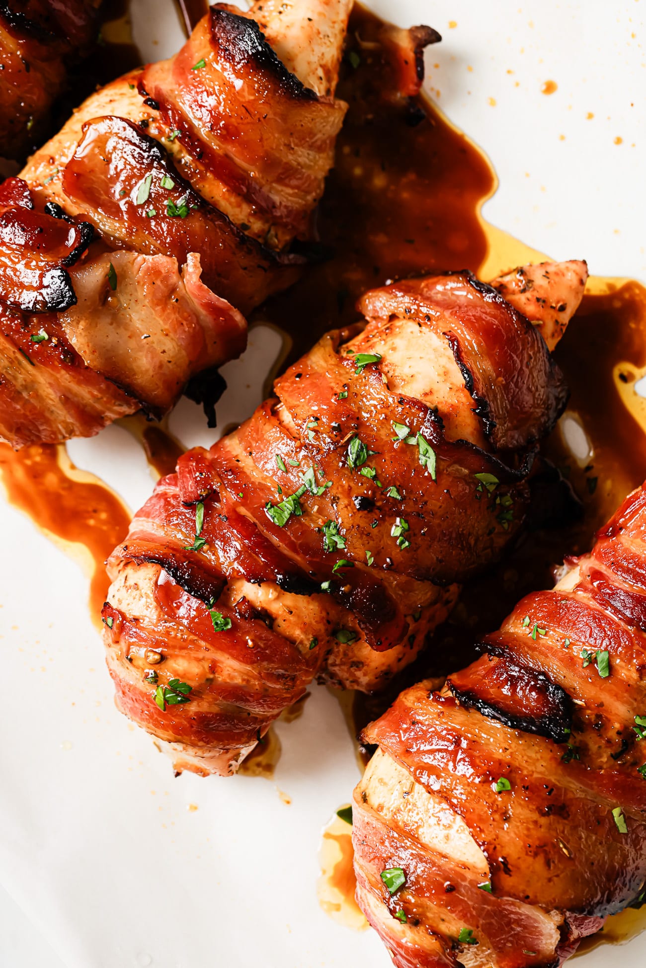 A close-up of bacon-wrapped chicken breasts garnished with parsley.