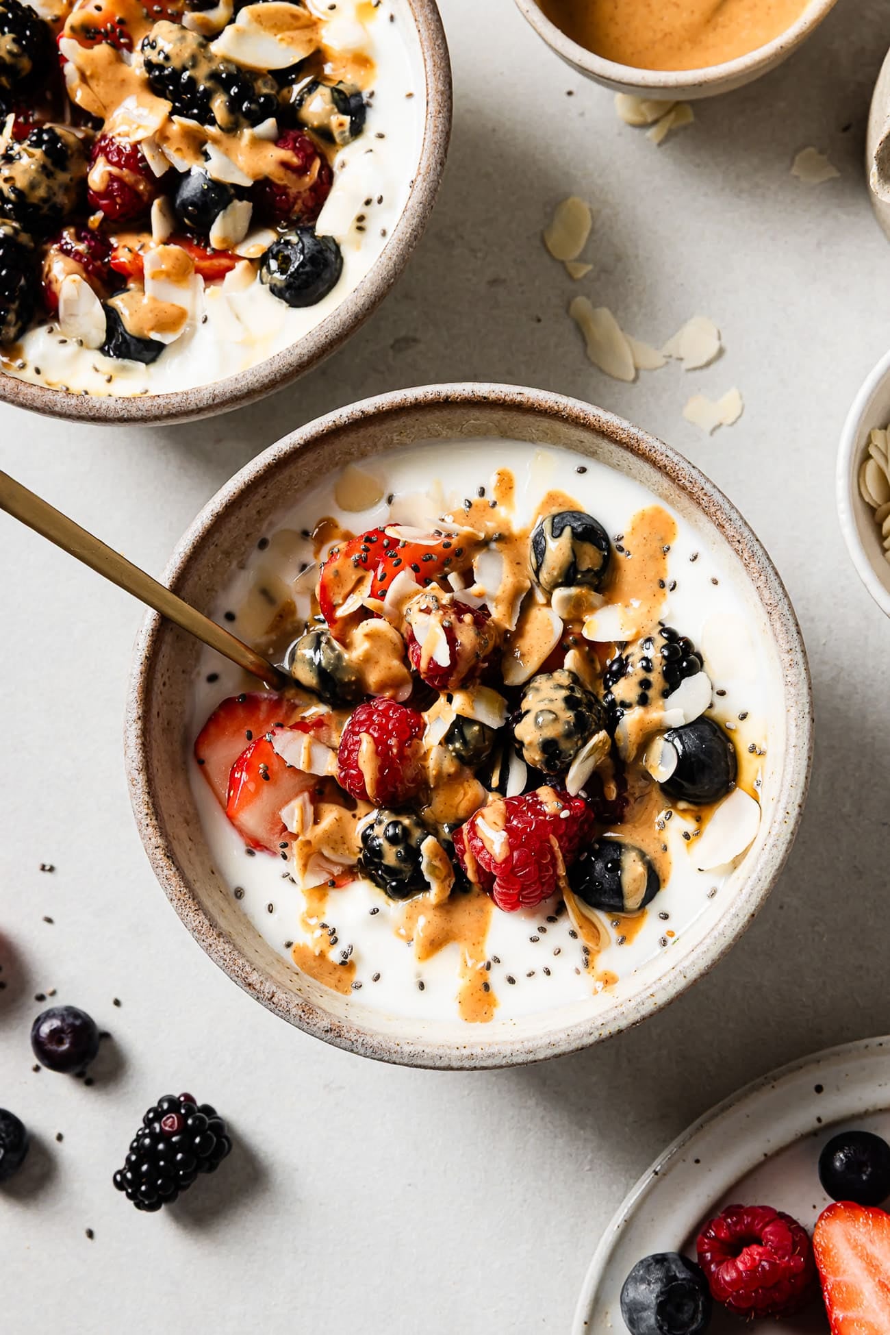 An overhead view of cottage cheese breakfast bowls topped with mixed berries, chia seeds, nuts, and syrup. 