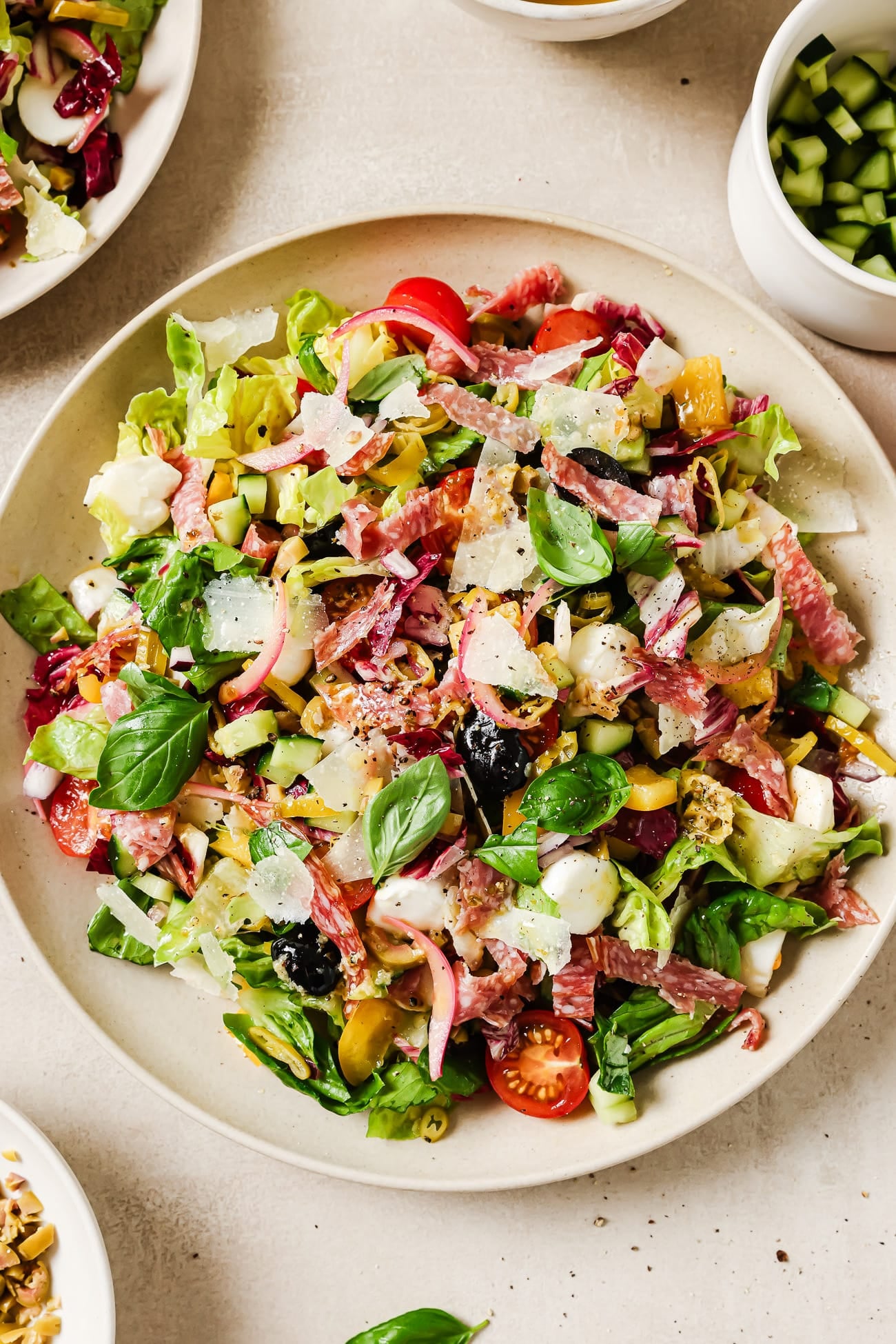 An overhead view of a large Italian chopped salad in a white serving bowl. 