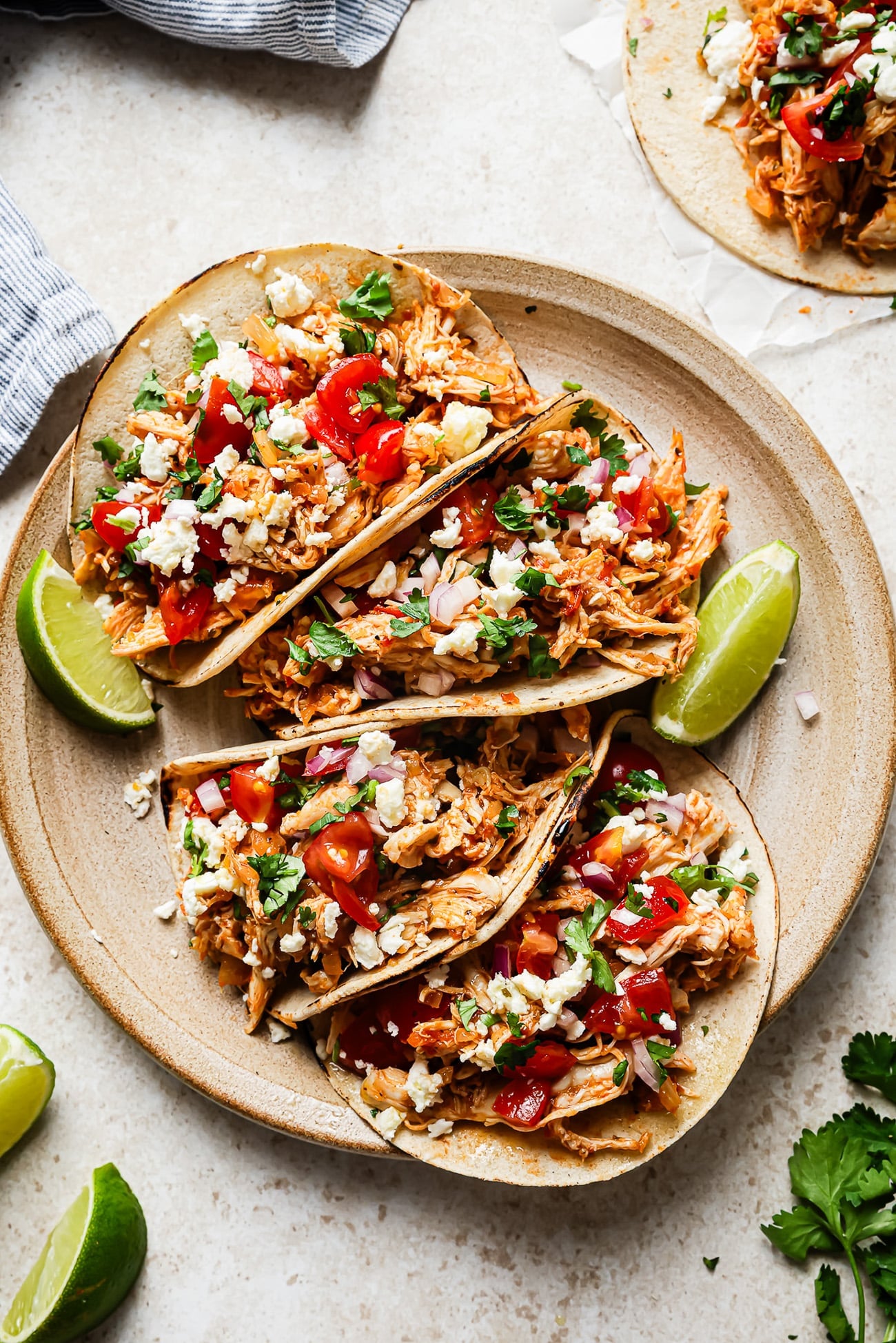 Overhead view of shredded chicken tacos served on a plate over a countertop.