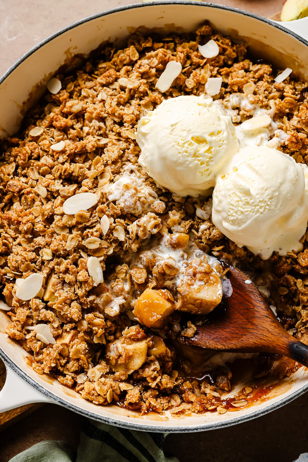 closeup view of gluten free apple crisp with vanila ice cream on top of it. 