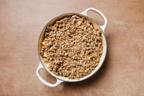 gluten-free apple crisp in a white skillet, ready to go to the oven.
