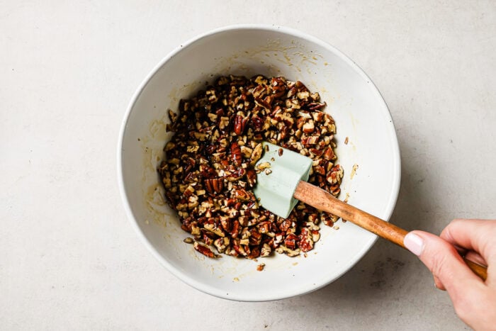 Pecan pie topping mixture in a white bowl with a spatula.