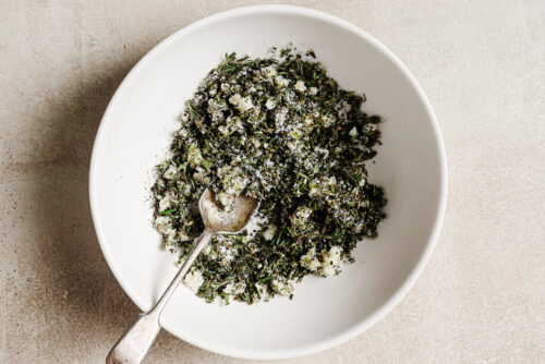 Fresh herbs and seasoning in a white bowl, ready to rub over the prime rib for roasting.