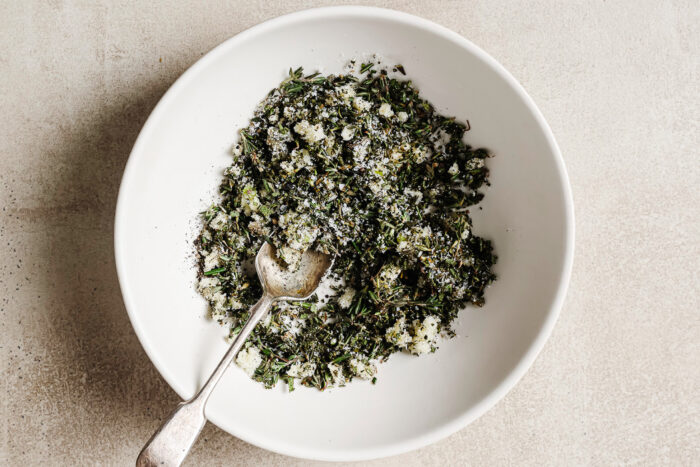 Fresh herbs and seasoning in a white bowl, ready to rub over the prime rib for roasting.