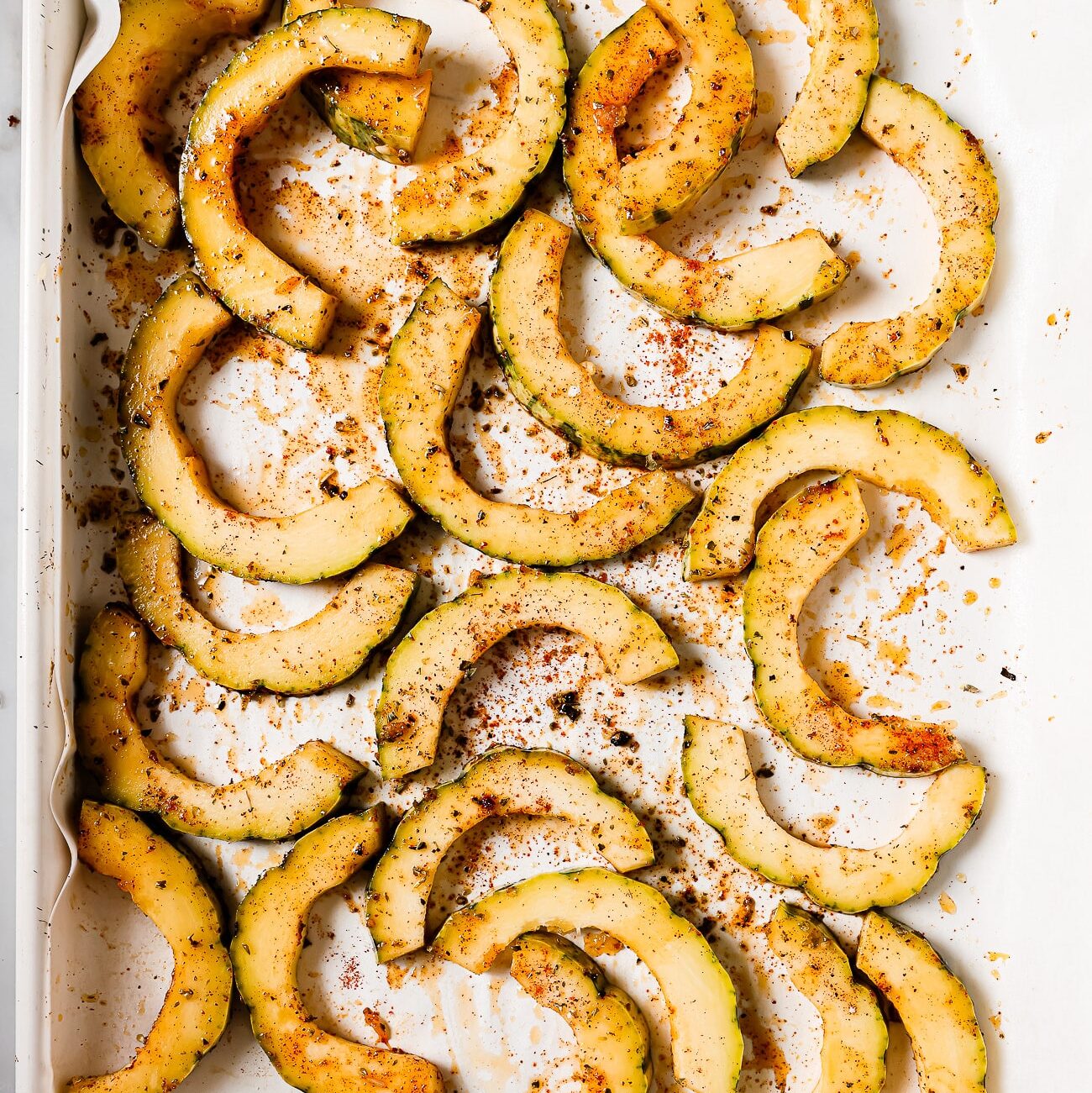 Seasoned squash slices on a baking sheet.