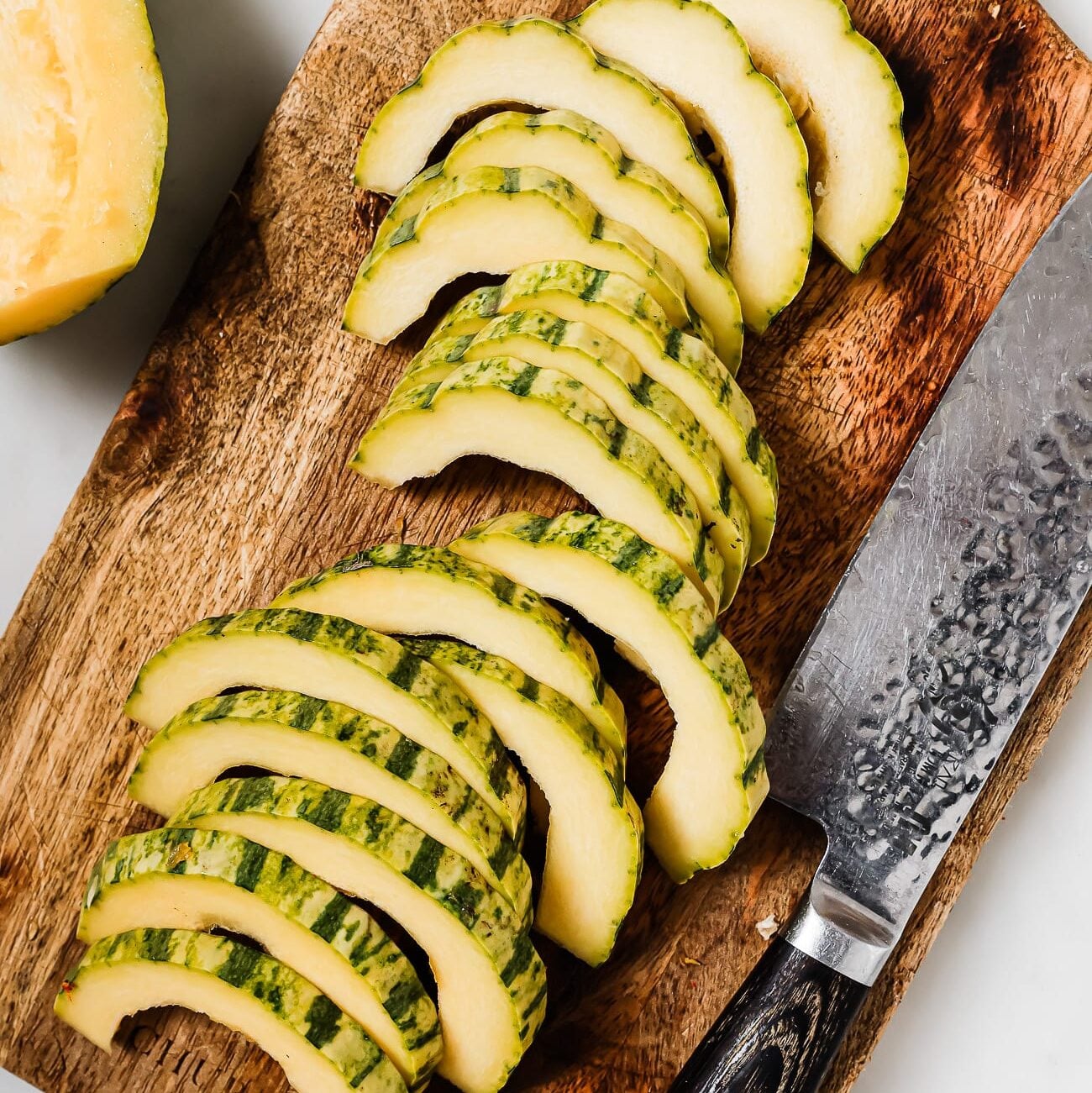 Delicata squash cut into cresent shaped slices.